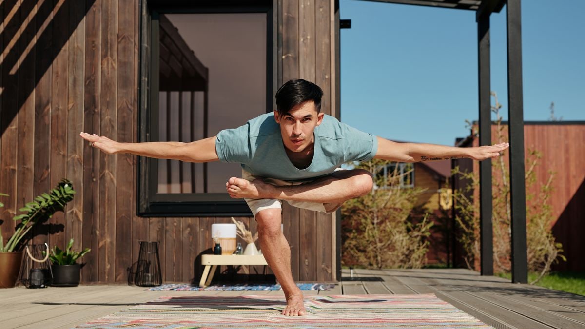 A man performing a yoga pose on a veranda outside, embracing a balanced and healthy lifestyle.
